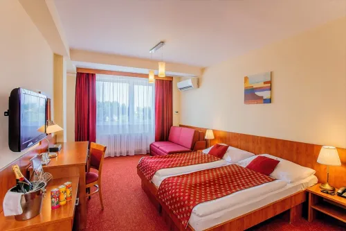 Manželská posteľ a prístelka v hotelovej izbe 